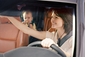 A woman driving a car uses an FM system to hear her baby in the back seat (Courtesy of Phonak)