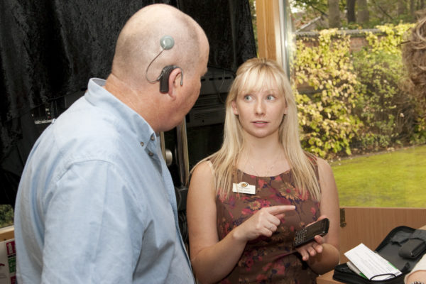 Man with cochlear implant talking to a woman