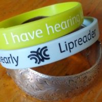 two silicon hearing loss wristbands and a metal bracelet