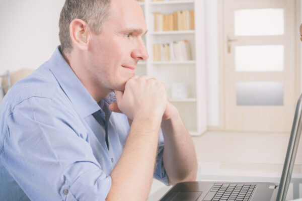 A man with hearing aids looking at a laptop