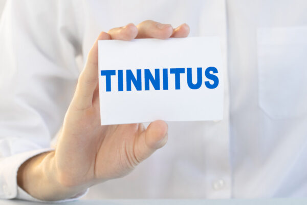 a hand holding a card with the word tinnitus