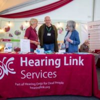 Peer support volunteer speaking to couple at information event and providing hearing information